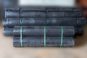 Image of a stack of rolls of heavy duty weed barrier landscape material from Howell Pathways. 